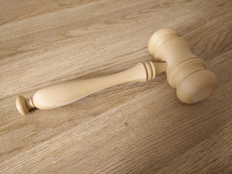 May include: A wooden gavel with a light brown finish. The gavel has a rounded head and a long handle.