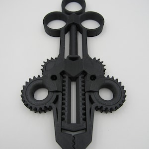 May include: A black, 3D printed, gear-shaped object with a pointed tip and four circular openings. The object has a complex design with multiple gears and interlocking parts.
