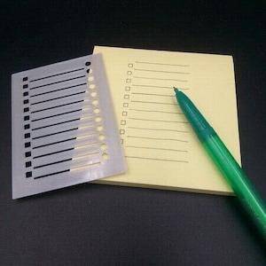 May include: A gray checklist with a grid of squares and lines, a yellow notepad with lines, and a green pen.