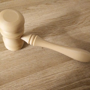 May include: A wooden gavel with a light brown finish. The gavel has a rounded head and a long handle.
