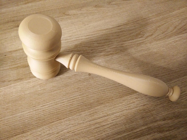 May include: A wooden gavel with a light brown finish. The gavel has a rounded head and a long handle.
