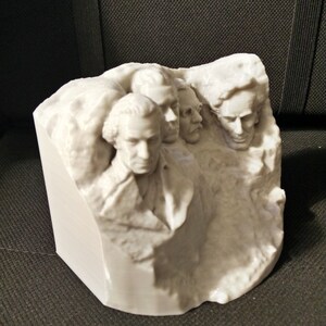 Pu&ograve; includere: Una scultura in 3D stampata in bianco del Monte Rushmore, con i volti di quattro presidenti scolpiti sul fianco di una montagna.