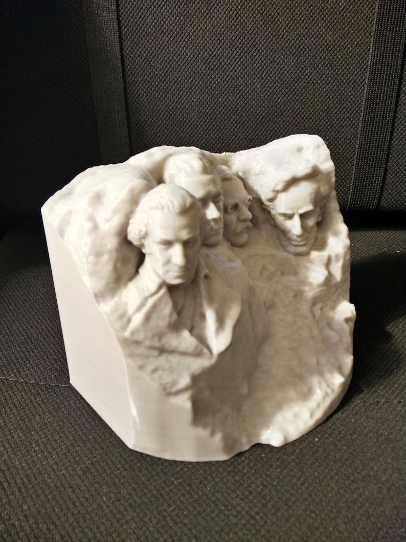 Pu&ograve; includere: Una scultura in 3D stampata in bianco del Monte Rushmore, con i volti di quattro presidenti scolpiti sul fianco di una montagna.