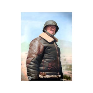 May include: A colorized image of a person wearing a military helmet and a brown leather bomber jacket with a cream-colored shearling collar. The jacket has a brown leather exterior and a dark brown interior. The person is standing in front of a light blue and tan background.