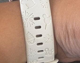 May include: A white silicone watch band with a pink watch face. The band has a repeating pattern of Mickey Mouse heads, fireworks, and ice cream cones.
