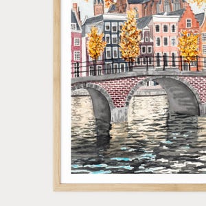 May include: Watercolour painting of a European cityscape with a brick bridge over a canal. Buildings of various styles line the canal, with autumn trees adding yellow and orange. The water reflects the buildings and sky.