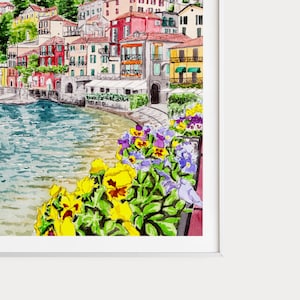 Peut inclure: Peinture &agrave; l'aquarelle d'un village italien color&eacute; avec des b&acirc;timents le long d'un front de mer. La sc&egrave;ne est encadr&eacute;e par une rang&eacute;e de fleurs jaunes, violettes et bleues vibrantes.