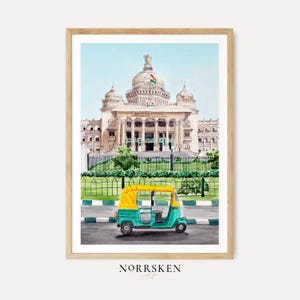 Puede incluir: Impresión en acuarela de un edificio grande y ornamentado con techo abovedado y columnas, con una bandera india. Un auto-rickshaw turquesa y amarillo está frente al edificio. La impresión está en un marco de madera. El nombre del artista, NORRSKEN Art, está en la parte inferior.