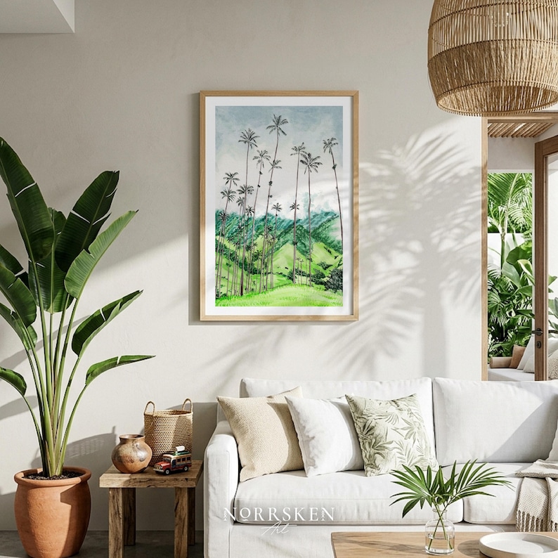 Pode incluir: Uma impress&atilde;o em aquarela emoldurada de uma paisagem com altas palmeiras em uma colina verde sob um c&eacute;u nublado. A obra de arte &eacute; exibida acima de um sof&aacute; branco em uma sala de estar, com uma grande planta em vaso e uma l&acirc;mpada tecida.