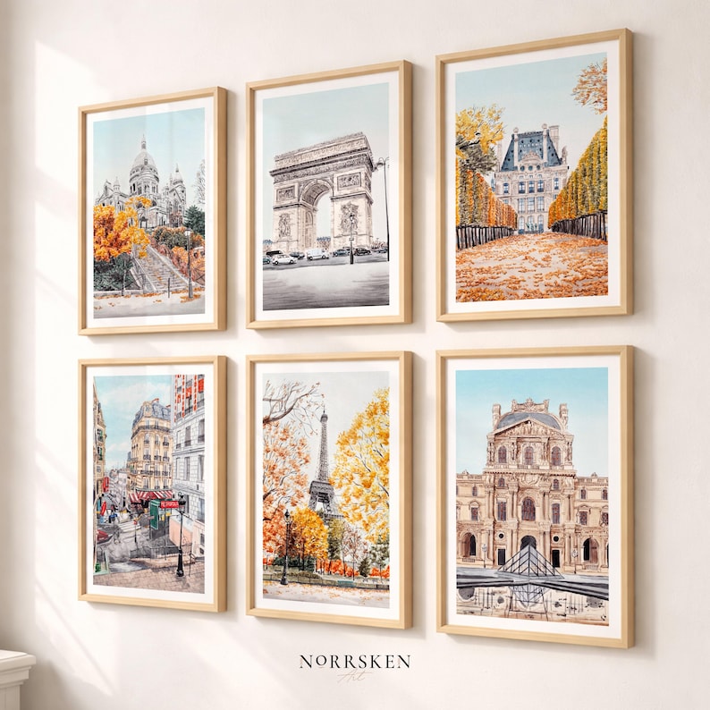 K&ouml;nnte beinhalten: Sechs gerahmte Aquarelldrucke von Pariser Wahrzeichen, darunter der Eiffelturm und der Arc de Triomphe. Die Kunstwerke zeigen Herbstfarben und sind in hellen Holzrahmen gefasst, was eine warme, einladende &Auml;sthetik erzeugt.
