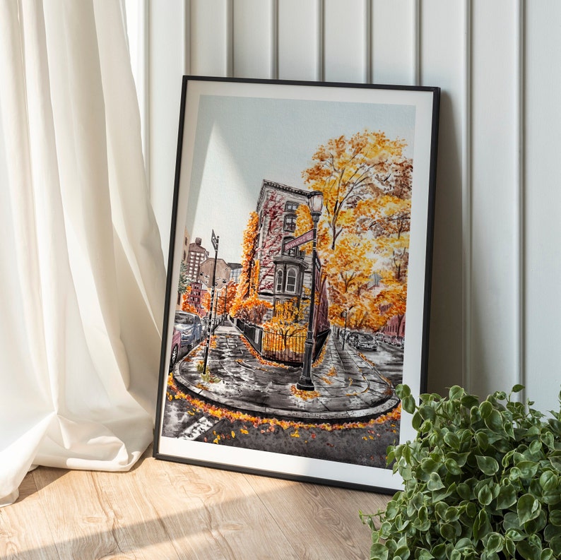 Puede incluir: Una pintura de acuarela de una escena de calle de la ciudad con follaje de oto&ntilde;o. La pintura presenta un edificio de ladrillo con una farola y un letrero que dice "The Corner Store". La calle est&aacute; bordeada de &aacute;rboles con hojas amarillas y naranjas.