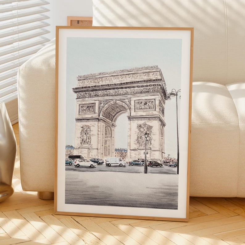 K&ouml;nnte beinhalten: Ein gerahmter Druck mit einer detaillierten Feder- und Tinte-Illustration des Arc de Triomphe in Paris. Das Kunstwerk f&auml;ngt die architektonischen Details des Denkmals ein, mit Autos und Stra&szlig;enlaternen. Der Druck ist in einem Holzrahmen.