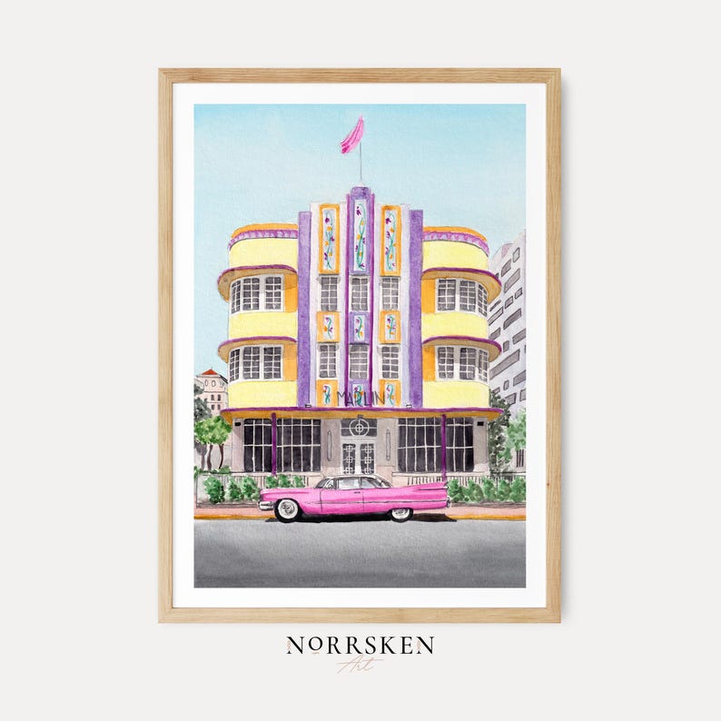 May include: A watercolor art print in a light wood frame depicting a yellow and purple Art Deco building with the word MARLIN on the facade. A long pink vintage car is parked in front of the building on a gray street under a clear blue sky.