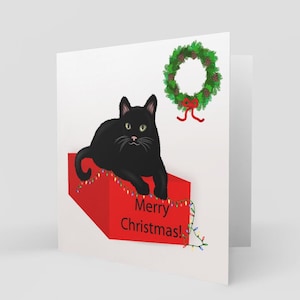Carte de voeux chat noir allongé sur une boîte de Noël, carte de chat de Noël, carte de Noël chat mignon, carte de Noël chat noir