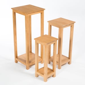 May include: Three wooden plant stands of varying heights. The stands are made of natural wood and have a simple, rectangular design.