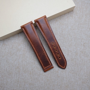 May include: Two brown leather watch straps with stitching around the edges.
