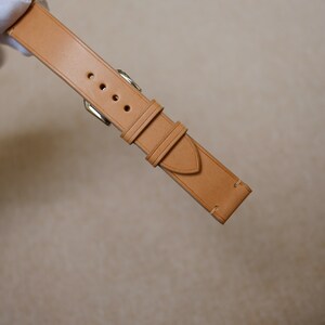 K&ouml;nnte beinhalten: Ein hellbraunes Lederarmband mit N&auml;hten und einer silbernen Schlie&szlig;e.