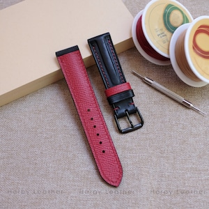 May include: Two watch straps, one red and one black with red stitching. The straps are made of leather and have a buckle closure.