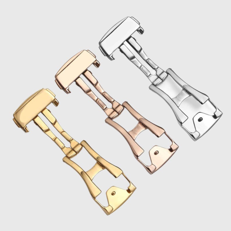 May include: Three watch band clasps in different finishes: silver, gold, and rose gold. Each clasp has a polished finish and a secure locking mechanism.