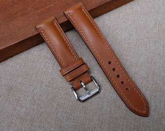 May include: Two brown leather watch straps with stitching detail. One strap has a silver buckle.
