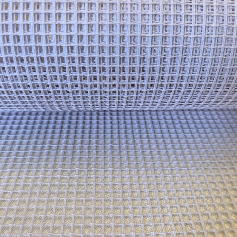 Puede incluir: Una tela de color gris claro que presenta una textura de tejido de gofre. El material se compone de un patr&oacute;n de cuadr&iacute;cula repetitivo de cuadrados elevados, creando una superficie tridimensional con profundidad visible y espaciado constante.