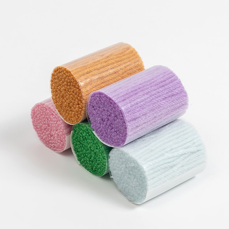 K&ouml;nnte beinhalten: F&uuml;nf Garnrollen in verschiedenen Farben: hellblau, gr&uuml;n, rosa, lila und orange. Das Garn ist um Pappr&ouml;hren gewickelt und bereit f&uuml;r Bastelprojekte.