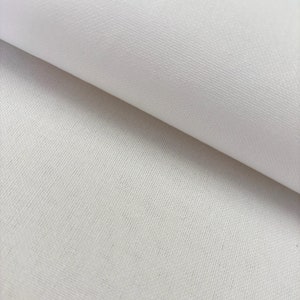 May include: Close-up of a white canvas fabric with a subtle texture. The fabric is folded over, revealing the smooth surface underneath.