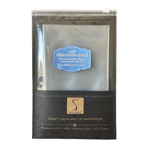 Könnte beinhalten: Eine schwarze Reißverschlusstasche mit einem transparenten Plastikfenster, in dem ein weißer wasserlöslicher 14-zählender Stoff liegt. Die Tasche hat ein schwarzes Etikett mit dem Text "SEW CRANE" und den Worten "CRAFT YOUR WAY TO HAPPINESS". Das Etikett enthält auch den Text "Needlecraft Fabrics | Aida | Embroidery Kits | More To Come".