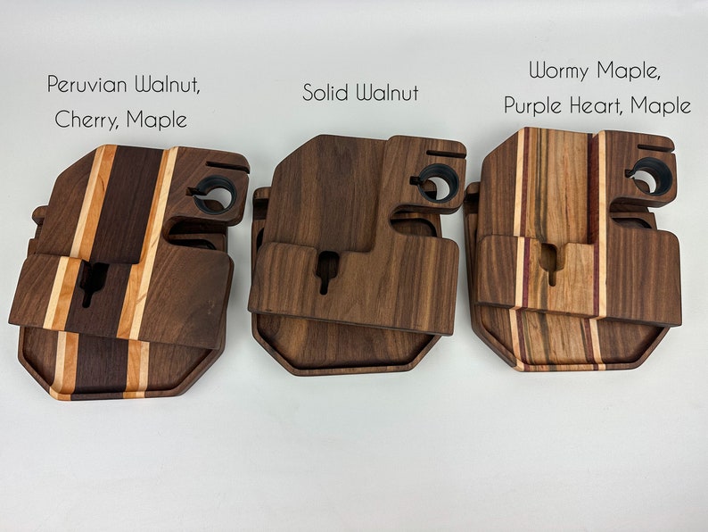 May include: Three wooden phone stands with different wood types. The first stand is made of Peruvian walnut, cherry, and maple. The second stand is made of solid walnut. The third stand is made of wormy maple, purple heart, and maple.
