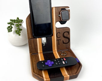 May include: A wooden phone and watch stand with a charging station for a phone. The stand has a tray for a remote control and a ring. The stand is personalized with the initials "C.T.S."