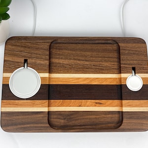 May include: A wooden charging station with two wireless charging pads, one for a phone and one for a watch. The station is made of walnut, maple, and cherry wood and has a natural finish.