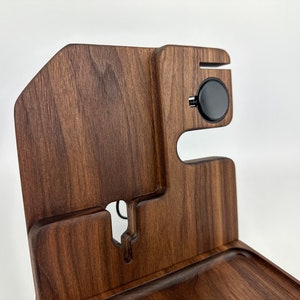 May include: A wooden organizer with a tray, a phone stand, and a wireless charging pad. The organizer is made of dark brown wood with a natural grain pattern.