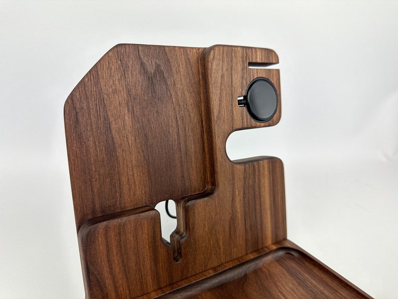 May include: A wooden organizer with a tray, a phone stand, and a wireless charging pad. The organizer is made of dark brown wood with a natural grain pattern.