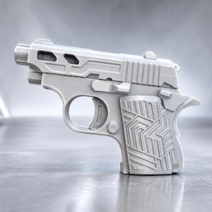 May include: A matte light gray toy pistol featuring a textured geometric pattern on the grip, a slide with cut-out details, a trigger, and a small barrel extension. The object is rendered in a solid, monochromatic finish with visible layer lines.