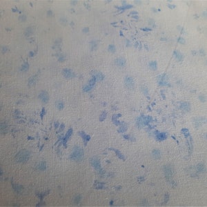 Könnte beinhalten: Ein weißer Stoff mit einem blauen Blumenmuster. Der Stoff hat eine subtile Textur und einen hellblauen Farbton.