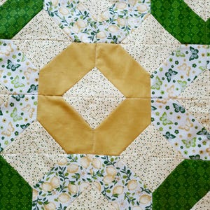 May include: A quilted fabric runner featuring a central mustard yellow octagon surrounded by cream fabric with small green dots. The design includes sections of white fabric printed with green and yellow butterflies and lemon patterns, bordered by green fabric.