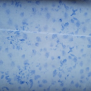Könnte beinhalten: Ein hellblauer Stoff mit weißem Hintergrund und einem verstreuten Muster aus blauen Flecken.