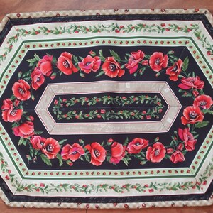 Könnte beinhalten: Sechseckiger Tischläufer mit schwarzem Hintergrund und einem Rand aus grünen Blättern, roten Beeren und weißen Punkten. Die Mitte zeigt ein Design aus roten Mohnblumen mit grünen Blättern auf schwarzem Hintergrund.