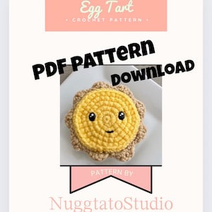 May include: Crochet pattern download for an egg tart shaped amigurumi toy. The toy is yellow with a brown crust and a smiling face. The pattern is by Nuggettatostudio.