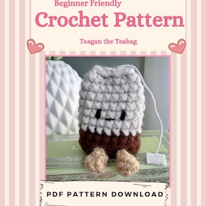 May include: A crochet pattern cover featuring a cute Teagan the Teabag design. The pattern is labeled "Beginner Friendly" and includes a photo of the finished product. The cover has a pink and white striped background with the text "PDF Pattern Download" and "By NuggatoStudio."
