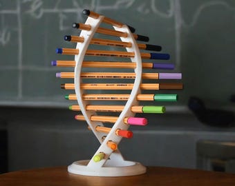 May include: A white 3D printed pencil holder shaped like a DNA helix. The holder is filled with colorful pencils, including green, blue, purple, pink, orange, and yellow.