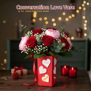 May include: A red vase with heart-shaped stickers bearing the words "Love", "Cutie Pie", and "Kiss Me" contains a floral arrangement of red roses, pink peonies, and foliage. The text "Conversation Love Vase" is visible.