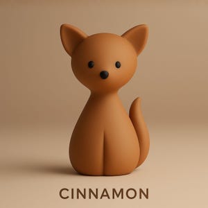 May include: A brown, stylized cat figurine with large ears, black eyes, and a small nose. The word "CINNAMON" is printed in capital letters at the bottom of the image. The cat has a smooth, matte finish and a curved tail.