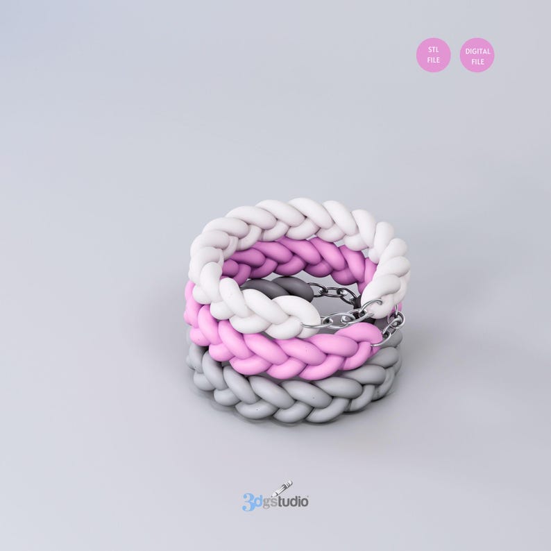 Op de afbeelding: Drie gevlochten armbanden gestapeld op elkaar. De bovenste armband is wit, de middelste armband is roze en de onderste armband is grijs.