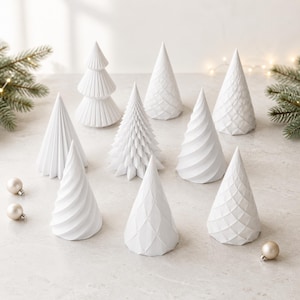 Puede incluir: Una colecci&oacute;n de nueve &aacute;rboles decorativos blancos en forma de cono con diversas texturas, incluyendo superficies plisadas, en espiral y con patrones de diamantes. El conjunto incluye peque&ntilde;os adornos redondos dispersos.