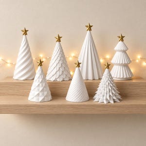 Puede incluir: Una colecci&oacute;n de siete &aacute;rboles decorativos blancos en forma de cono de diversas alturas y texturas, cada uno rematado con una peque&ntilde;a estrella dorada. Los &aacute;rboles presentan diversos patrones, incluyendo espirales, escamas, facetas y estr&iacute;as.