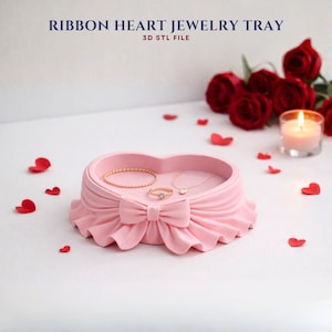 May include: A pink heart-shaped jewelry tray with a ribbon design, holding a gold bracelet, ring, and necklace. The tray is surrounded by red rose petals and roses. Text at the top reads "RIBBON HEART JEWELRY TRAY 3D STL FILE."