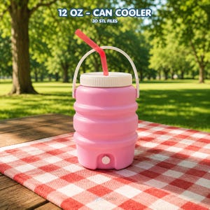 May include: A pink can cooler with a white lid, handle, and a red straw. The cooler is designed to hold 355 ml. It sits on a red and white checkered picnic blanket. The text "12 OZ - CAN COOLER" and "3D STL FILES" are printed on the top.
