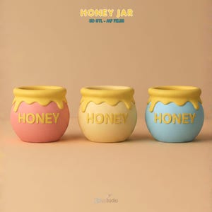 May include: Three honey jars in pink, yellow, and blue, each with a yellow honey-like rim and the word "HONEY". These 3D models are ideal for decorative purposes. The jars are in a studio setting.