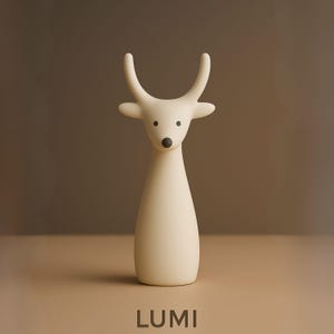 May include: A cream-colored deer figurine with curved antlers, black eyes, and a black nose. The deer has a slender body and is standing on a neutral-toned surface. The word "LUMI" is printed at the bottom of the image.